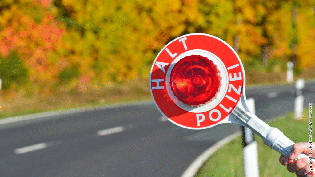 Polizeikelle zeigt Halt auf Landstraße im Herbst, Deutschland. Verkehrskontrolle mit farbiger Laubkulisse.