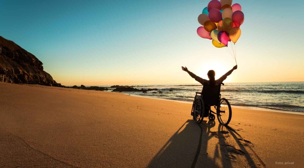Person im Rollstuhl genießt den Sonnenuntergang am Strand, hält bunte Luftballons, Symbol für Freiheit und Lebensfreude.