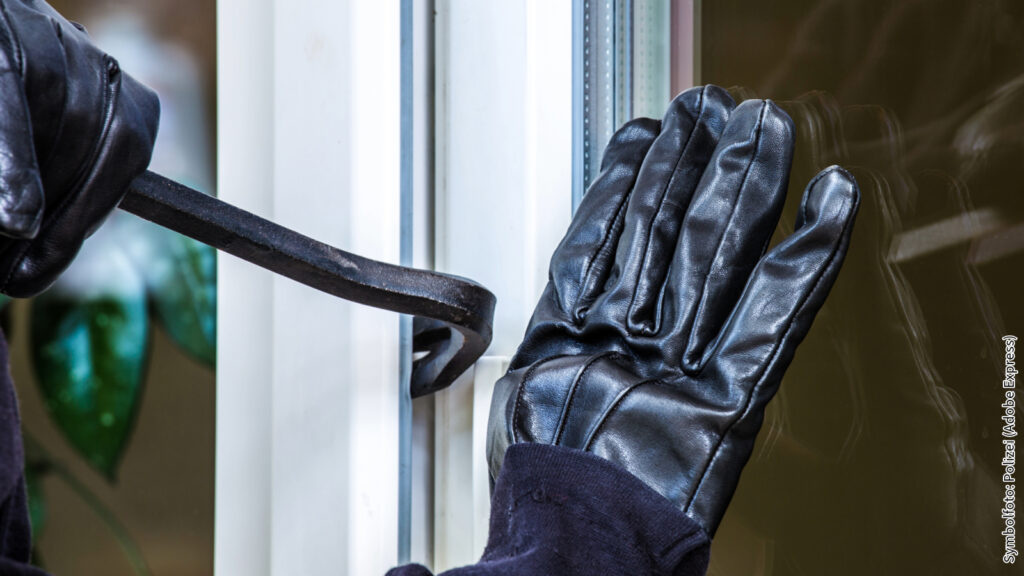 Einbrecher versucht mit Brechstange in Fenster einzudringen. Symbolbild für Sicherheit und Schutzmaßnahmen.