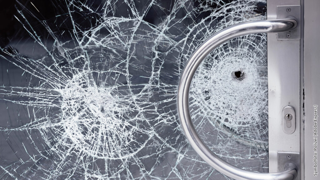 Zerbrochene Glastür mit Einschussloch und Edelstahlgriff, Nahaufnahme. Sicherheit und Vandalismus Thema.