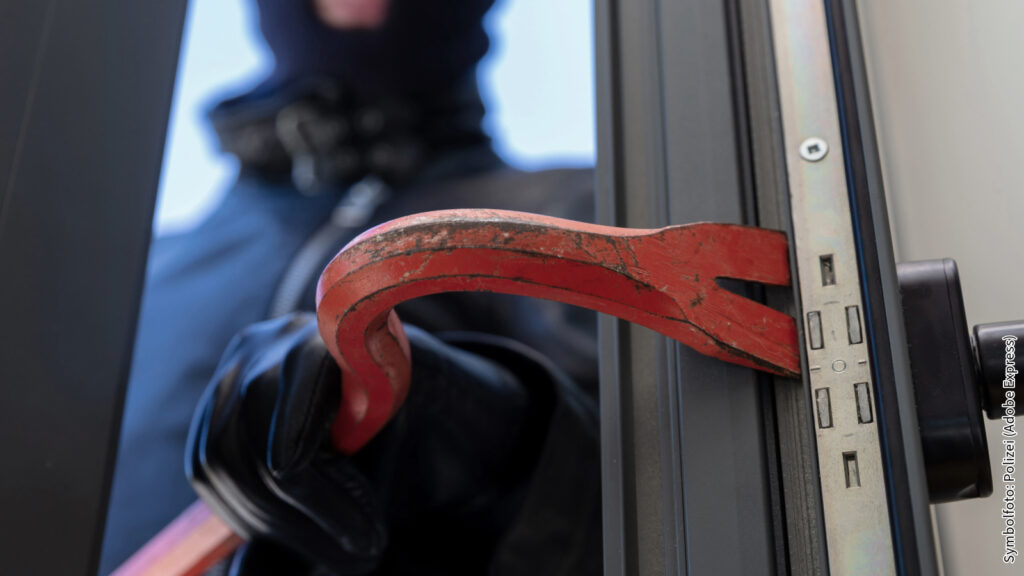 Einbrecher mit Brecheisen öffnet gewaltsam Türspalt – Sicherheitsgefahr und Einbruchschutz – Symbolfoto.
