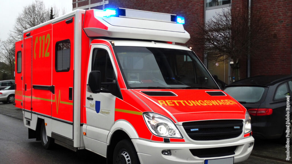 Rettungswagen mit eingeschaltetem Blaulicht auf Stadtstraße, bereit für Notfalleinsatz, ansicht von schräg vorn.