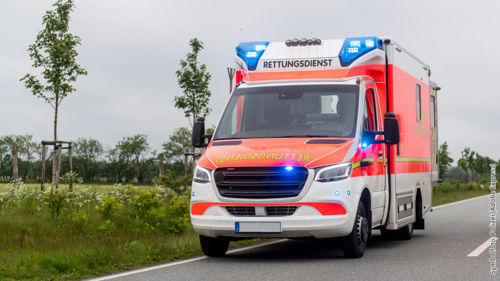 Krankenwagen auf Landstraße mit Blaulicht, Rettungsdienst, Notfallfahrzeug im Einsatz, ländliche Umgebung, Tagaufnahme.