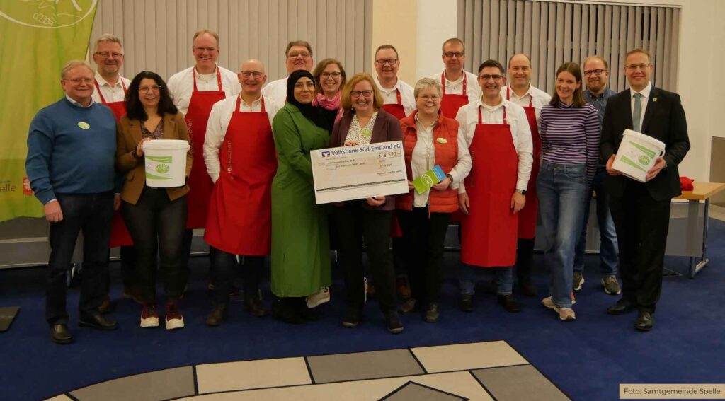 Die Piepkuchenbäcker (mit roten Schürzen, von links) Andreas Robin, Martin Rekers, Andreas Brüggemann, Stefan Heeke, Andreas Teders, Ludger Schröer, Reiner Baltes und Klaus Sändker übergeben die Spende an den Hilfsfonds WIR in der Samtgemeinde Spelle.