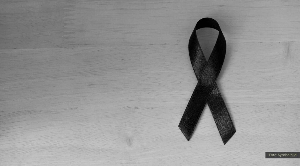 Schwarzer Trauerflor auf Holzuntergrund symbolisiert Trauer und Gedenken.