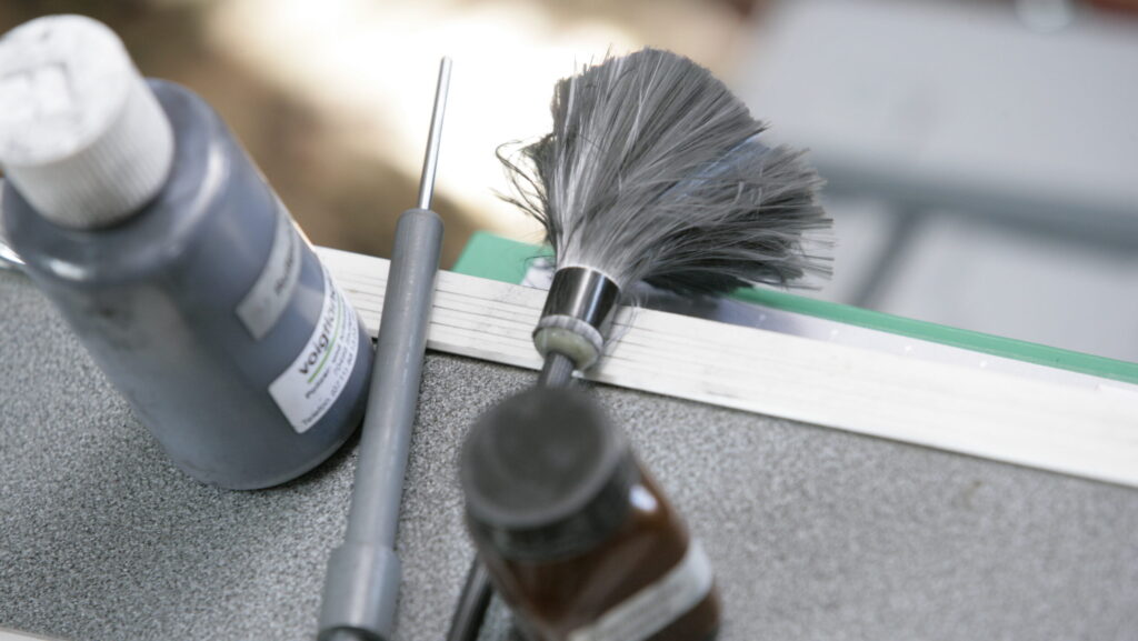 Staubpinsel und Flaschen auf Tisch, Nahaufnahme forensischer Werkzeuge für Spurensicherung.