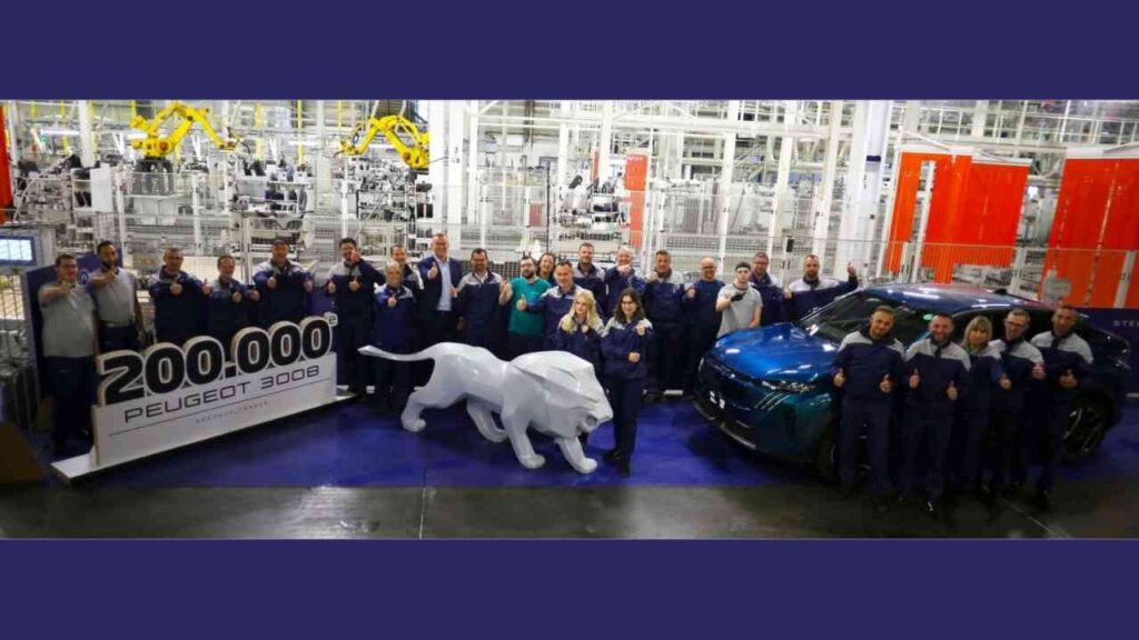Peugeot Team feiert Produktion des 200.000. Peugeot 3008 im Werk, mit großem Löwen und blauem Auto im Hintergrund.