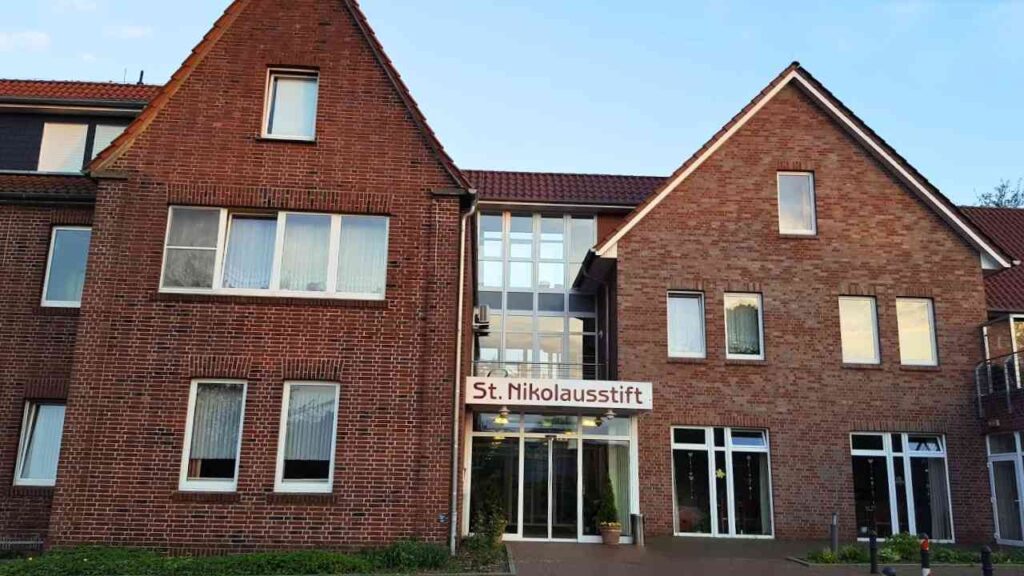 Backstein-Gebäude des St. Nikolausstifts bei klarem Himmel, mit großen Fenstern und einem zentralen Eingang.