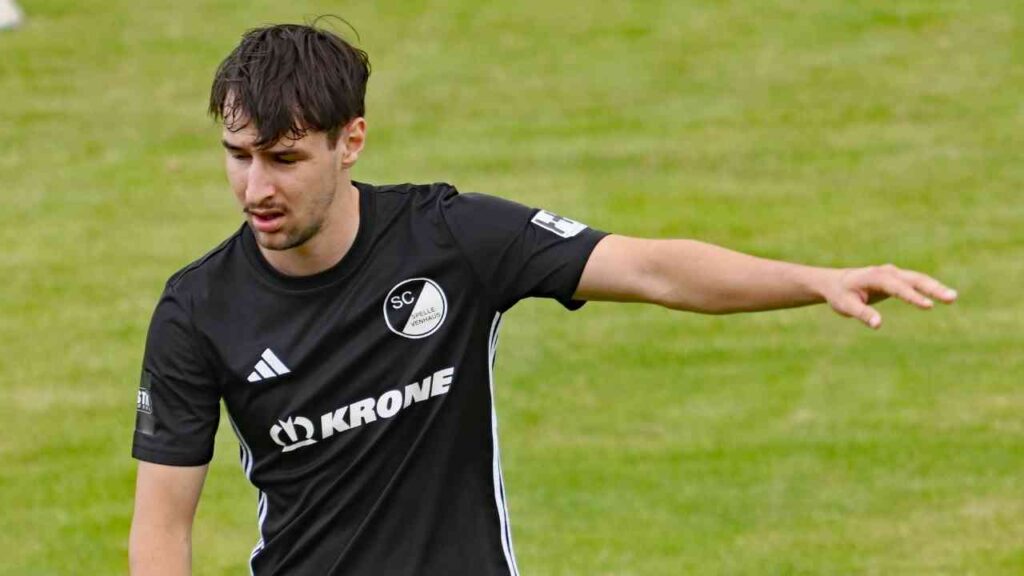 Ein Fußballspieler im schwarzen Trikot des SC Neustadt auf dem Spielfeld, hebt den Arm zur Kommunikation.