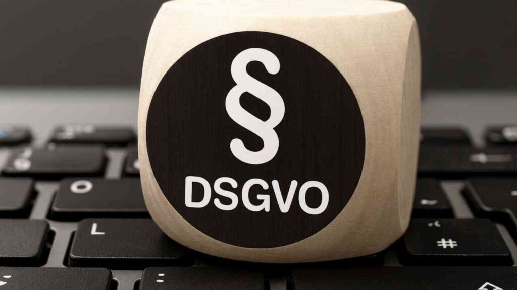 Holzwürfel auf Tastatur mit DSGVO-Symbol, zeigt Datenschutzrelevanz im digitalen Umfeld.