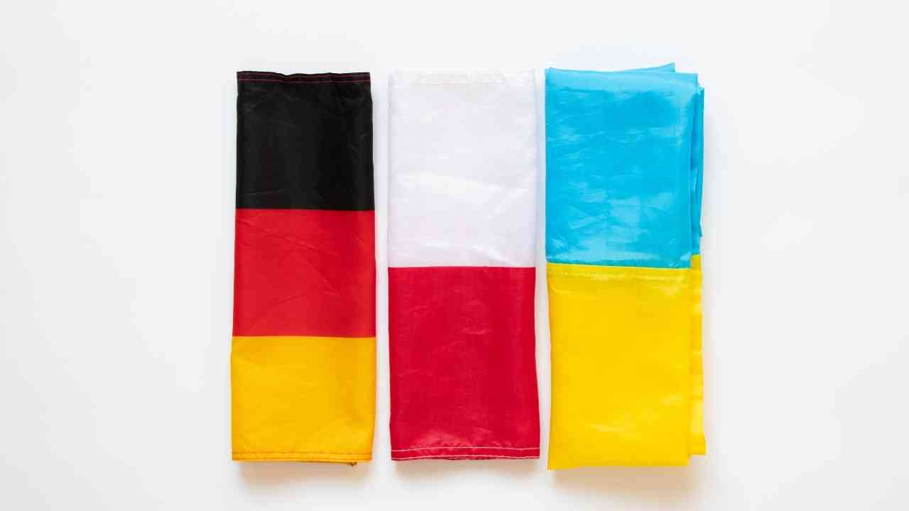 Drei gefaltete Flaggen: Deutschland, Polen und Ukraine auf weißem Hintergrund, symbolisieren europäische Vielfalt.