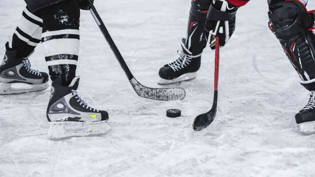 Eishockey-Spieler kämpfen um den Puck auf dem Eisfeld, beide ausgestattete in Schutzausrüstung und Schlittschuhen.