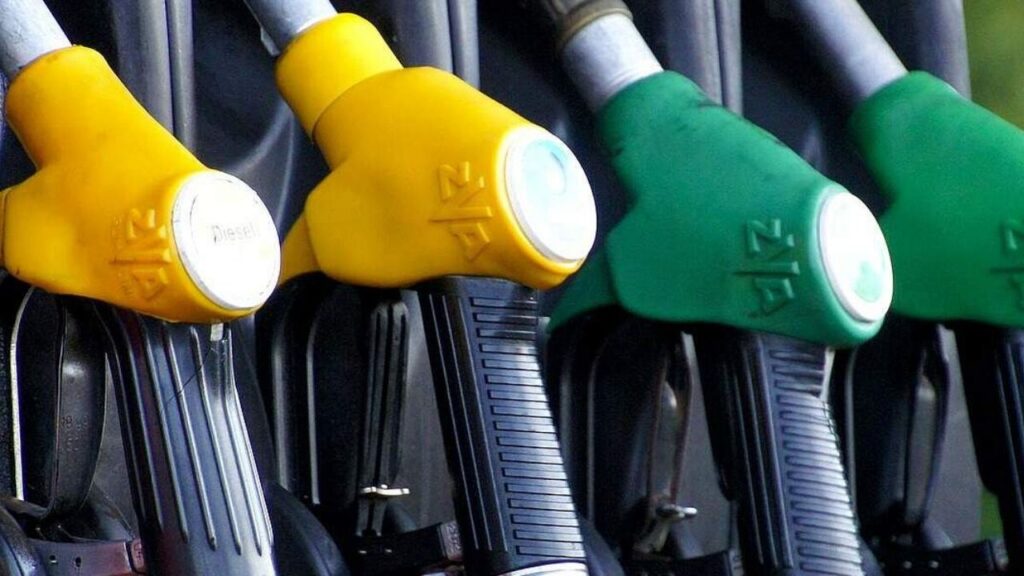 Zapfpistolen an einer Tankstelle, gelb für Diesel und grün für Benzin, in Nahaufnahme.