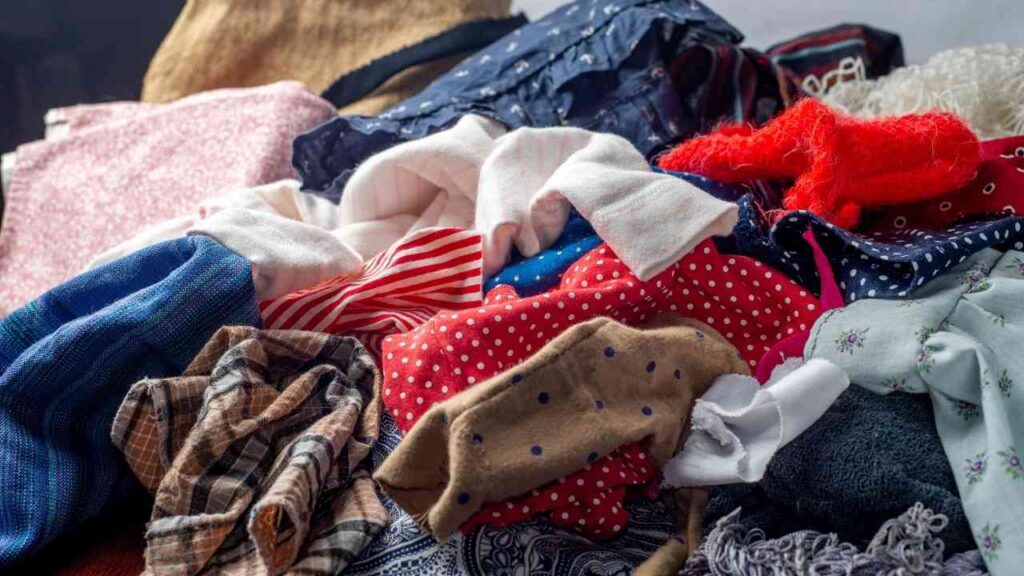 Bunter Haufen aus Altkleidern und Stoffresten in unterschiedlichen Mustern und Farben auf einem Haufen.