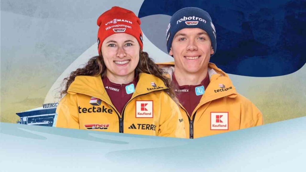 Zwei Sportler in gelben Jacken mit Sponsorenlogos lächeln vor einem blauen Hintergrund in die Kamera.