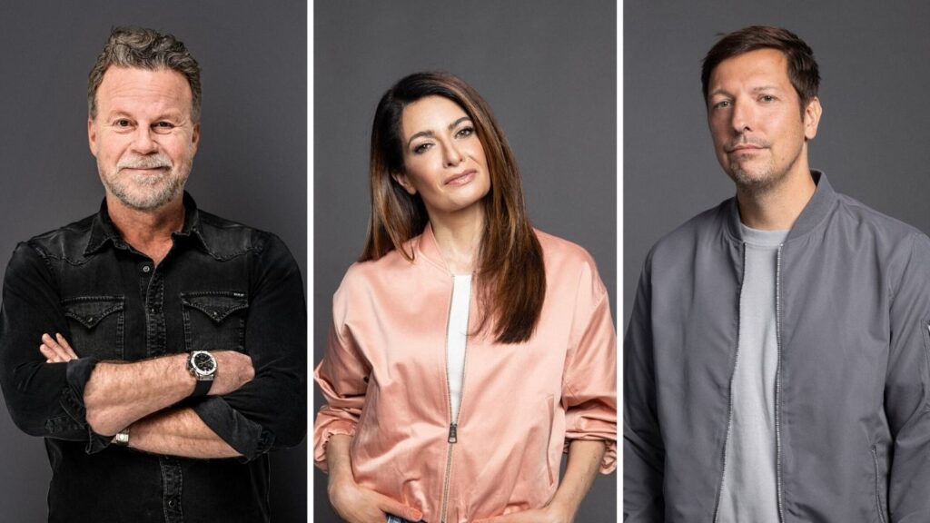 Drei Personen in lässiger Kleidung vor grauem Hintergrund, lächelnd in die Kamera schauend.