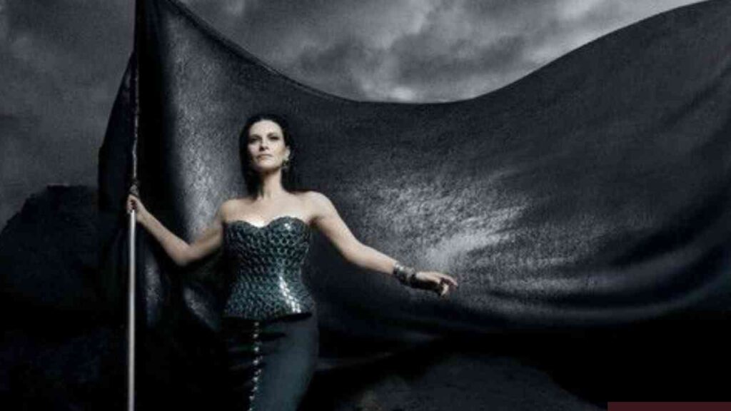 Frau in glamourösem Kleid steht mit Fahne vor stürmischem Himmel, symbolisiert Stärke und Entschlossenheit.