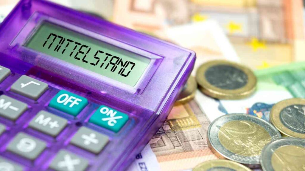 Lila Taschenrechner zeigt Mittelstand, umgeben von Euro-Münzen und -Scheinen, symbolisiert Finanzen im deutschen Mittelstand.