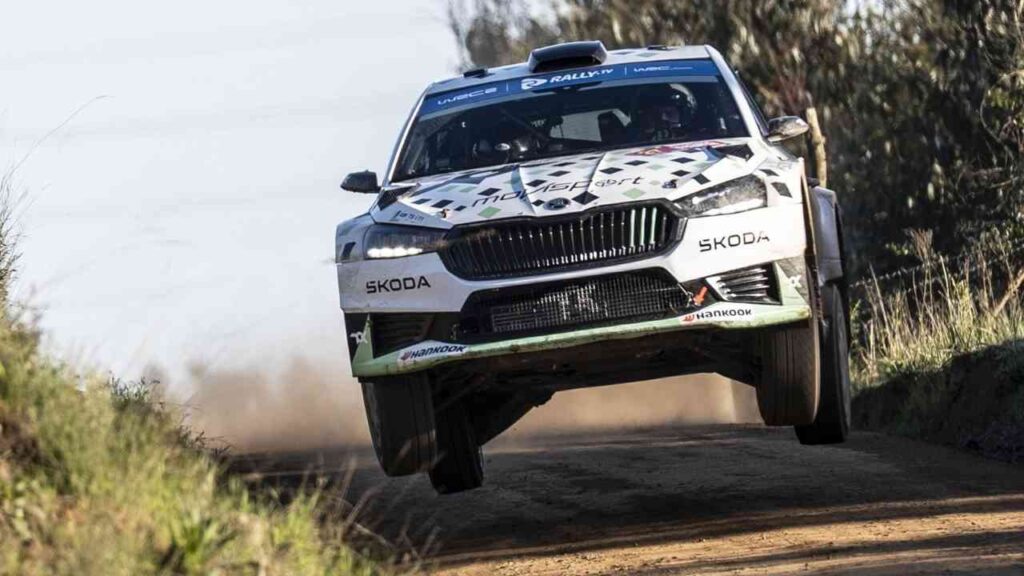 Rallyeauto hebt auf sandiger Strecke ab, dynamische Fahrt im Freien mit Skoda-Logo in Aktion.