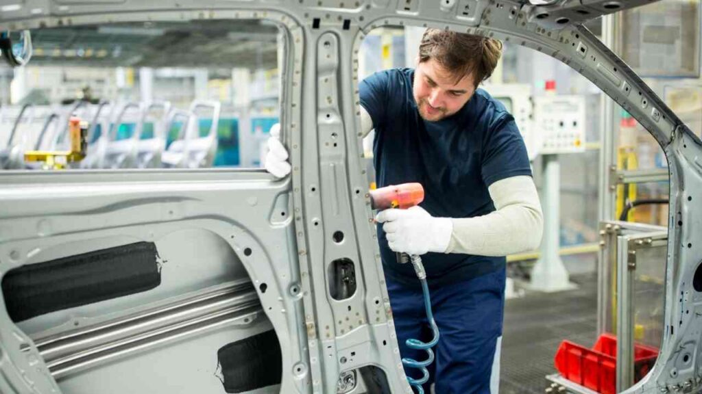 Arbeiter montiert Autoteile in der Fabrik, Herstellerindustrie, Fertigung, Automobilproduktion, präzises Handwerk.