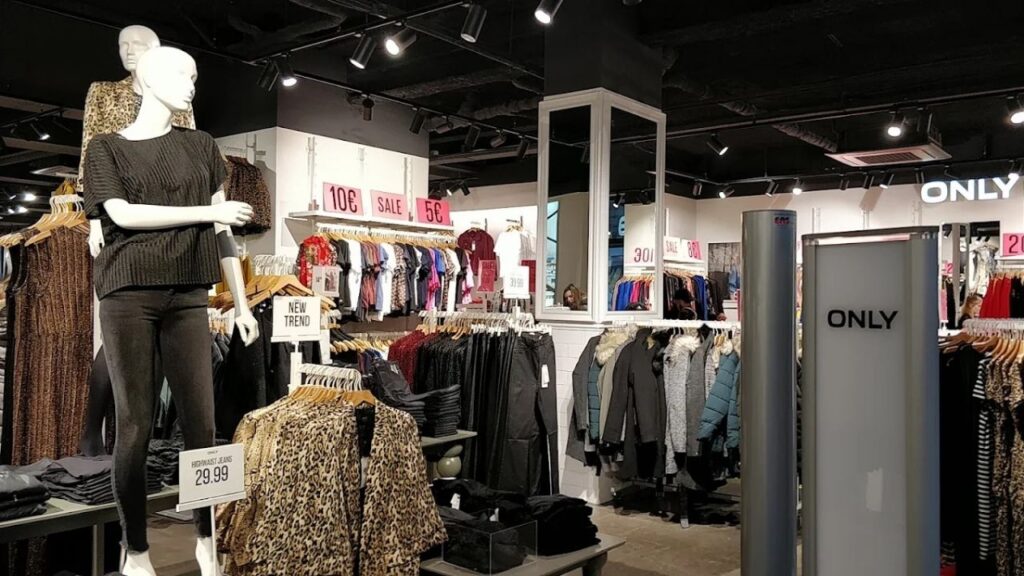 Modegeschäft Innenansicht mit Schaufensterpuppen, Kleidung auf Kleiderständern und SALE-Schildern.