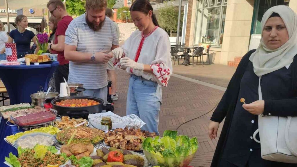 Straßenfest mit Menschen, die traditionelle Gerichte an einem Tisch mit vielfältigen Speisen servieren.