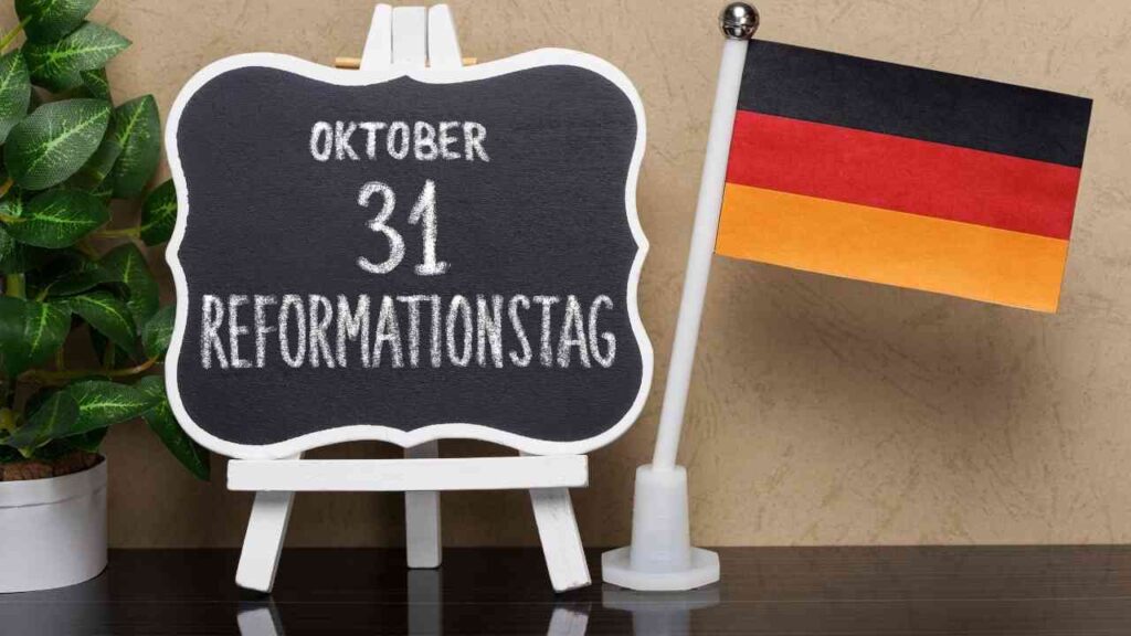 Tafel mit Reformationstag 31. Oktober neben deutscher Flagge und Pflanze. Feiertag Gedenken in Deutschland.