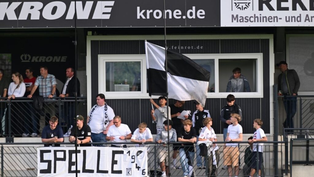 Fußballfans auf der Tribüne mit Banner und Flagge, zeigen ihre Unterstützung beim Spiel in Spelle.