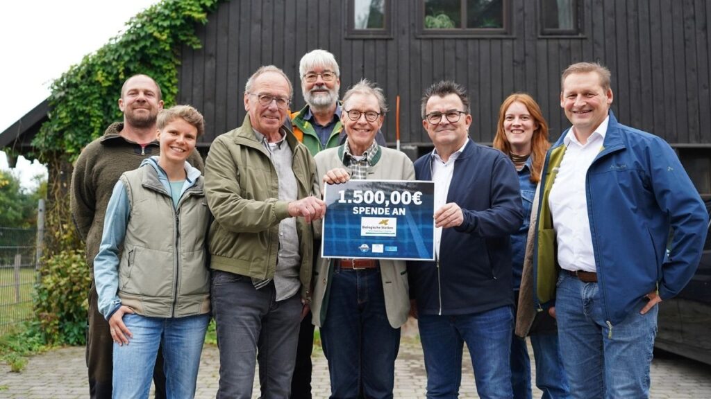 Gruppe von Menschen überreicht Spende von 1.500 Euro an Biologische Station vor einem Gebäude.