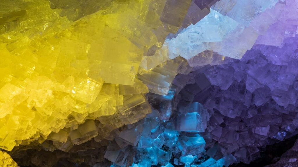 Bunte Kristallformationen in Gelb, Blau und Violett, die eine faszinierende Gesteinsszene bilden.