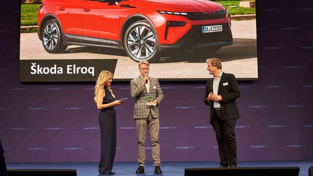 Personen präsentieren Škoda Elroq bei IAA 2023 auf der Bühne. Rotes Auto auf Display im Hintergrund.