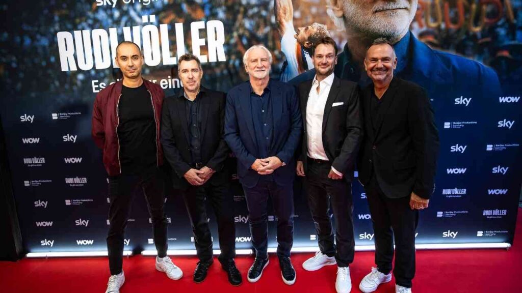 Gruppe von fünf Männern vor einem Poster bei einer Filmpremiere auf dem roten Teppich.