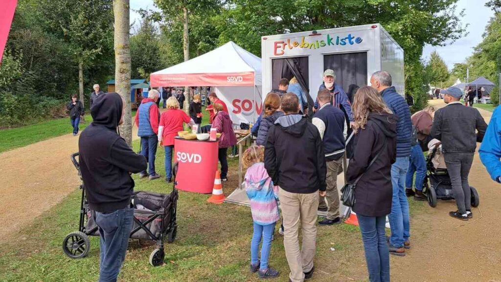 Menschen versammeln sich bei einem SOVD-Stand im Freien. Ein buntes Erlebnisangebot wird präsentiert.