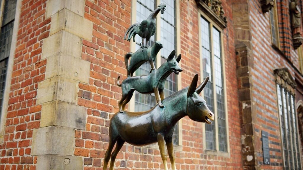 Statue der Bremer Stadtmusikanten vor Backsteingebäude in Bremen.