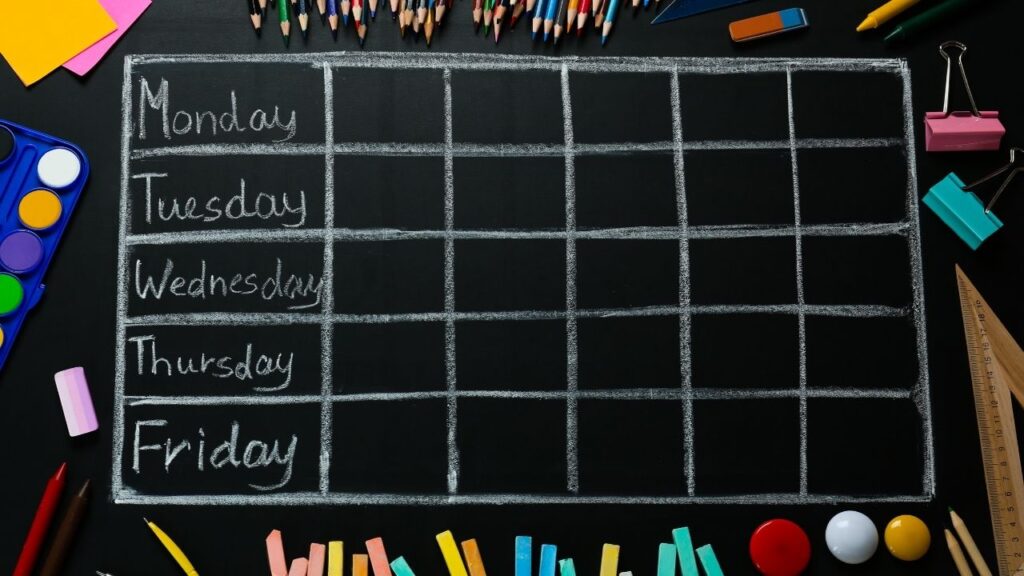 Leerer Wochenplan auf einer Kreidetafel, umgeben von Buntstiften und Bastelutensilien. Perfekt für Schul- und Lernplanung.