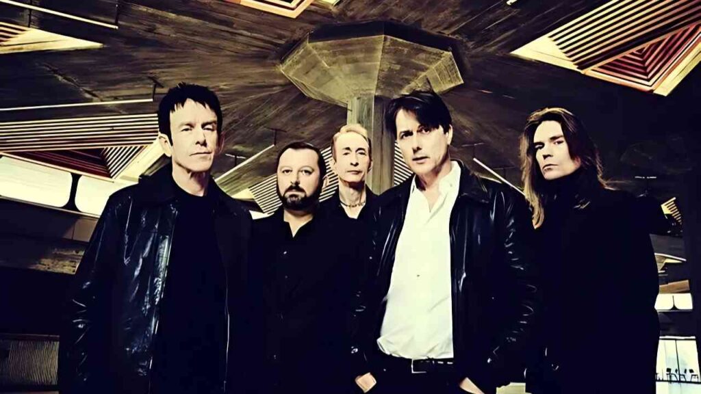 Fünf Männer in Lederjacken posieren in einem architektonisch interessanten Raum mit geometrischen Formen an der Decke.