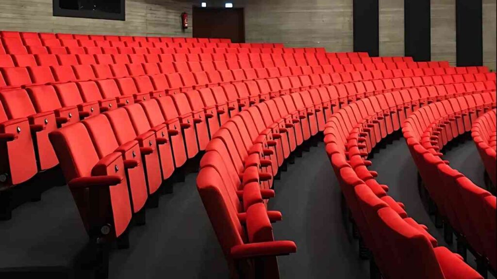 Leere rote Kinositze in einem modernen, gebogenen und gut beleuchteten Theatersaal.