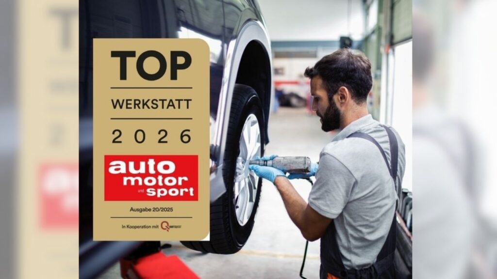 Mechaniker arbeitet an Fahrzeugreifen, neben einem Schild: Top Werkstatt 2026 von auto motor und sport.