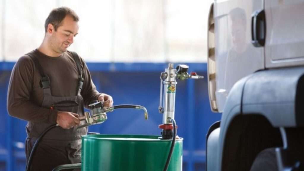 Mann betankt LKW mit Kraftstoff an einer Tankstelle im Freien, konzentriert bei der Arbeit.