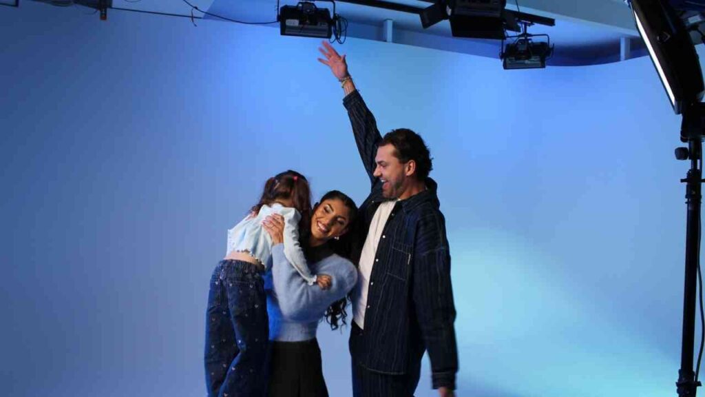 Glückliche Familie lachend vor blauem Hintergrund im Fotostudio, Eltern und Kind in innigem Moment vereint.