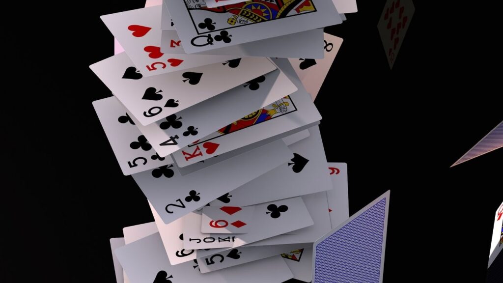 Stapel von Spielkarten, die in der Luft schweben, auf schwarzem Hintergrund. Kartenhaus im freien Fall.