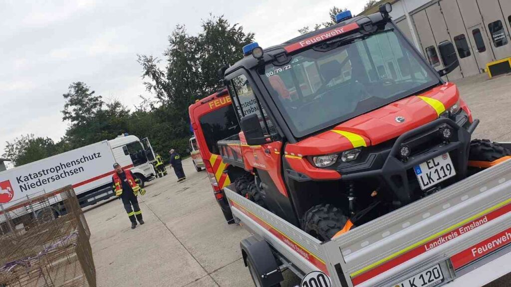 Feuerwehrauto und Katastrophenschutzfahrzeug Niedersachsen im Einsatz, Feuerwehrleute stehen bereit.