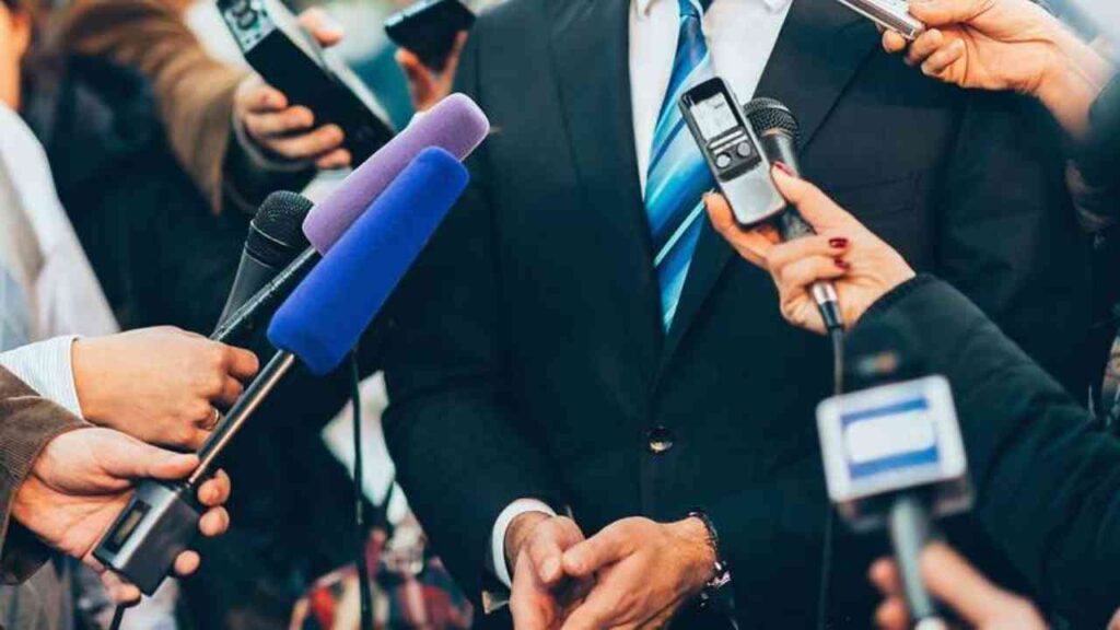 Person im Anzug vor Mikrofonen bei einer Pressekonferenz, Medieninterview, Journalismus, aktuelle Nachrichtenveranstaltung.