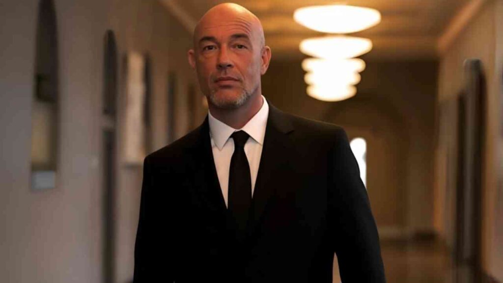 Ein Mann in eleganter Kleidung geht durch einen beleuchteten Flur, der elegante Atmosphäre ausstrahlt.