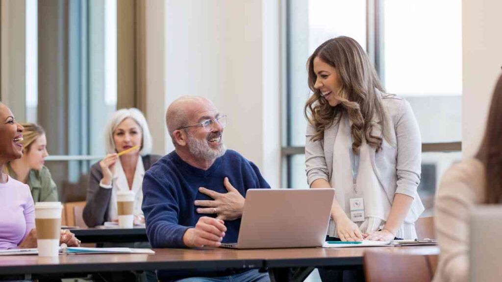 Freundliche Lehrerin hilft Schülern in einer Klassenzimmerumgebung, lächelnd und mit einem Laptop.