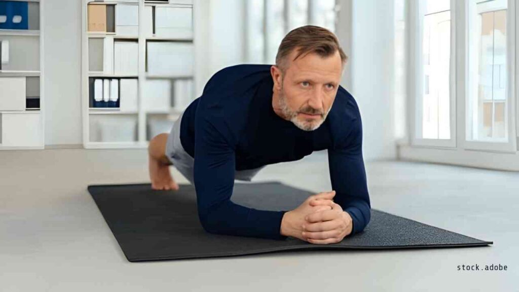 Mann in Plank-Position auf einer Matte, konzentriert und in sportlicher Kleidung.
