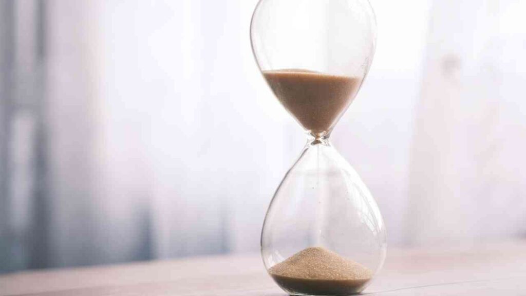 Glas Sanduhr mit feinem Sand, der von der oberen in die untere Kammer fließt.