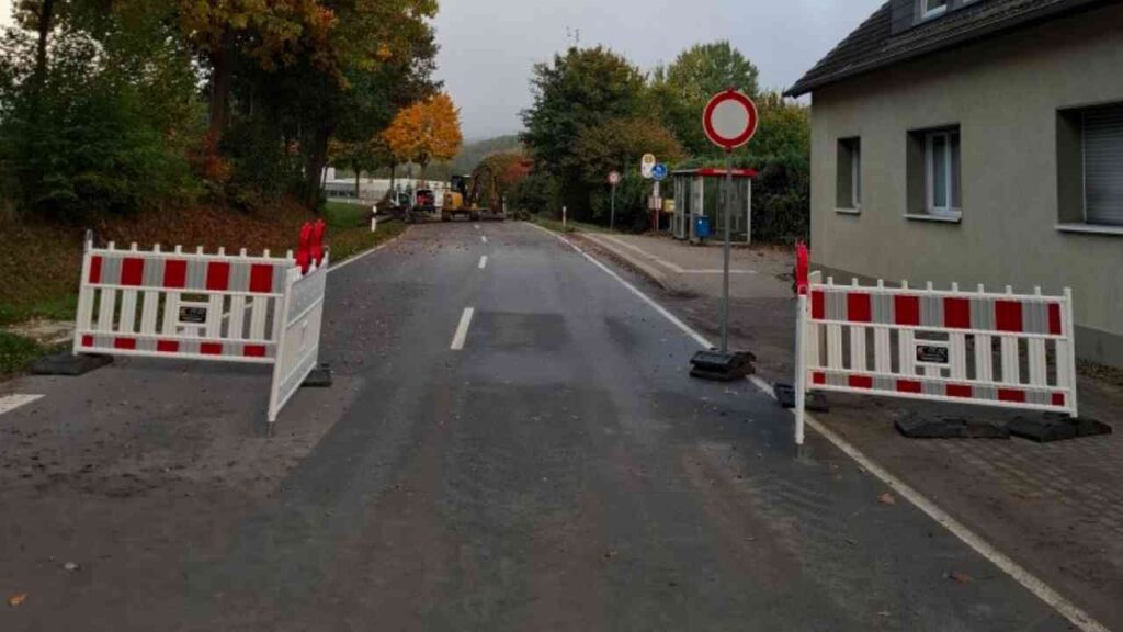 Baustelle mit Absperrungen auf einer Straße, die den Verkehr blockiert.