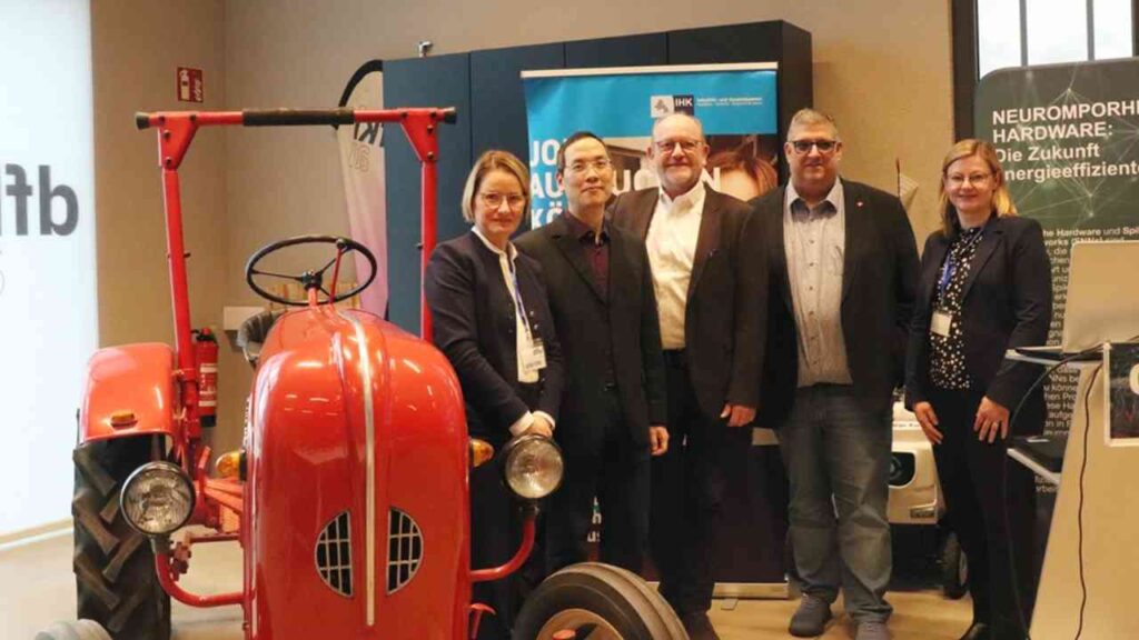 Roter Traktor mit fünf Personen in formeller Kleidung, die an einer Veranstaltung teilnehmen.