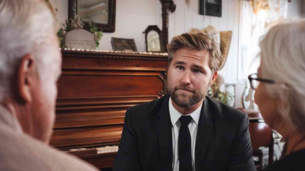 Ein Bestattungsfachkraft im Anzug spricht mit einem älteren Paar in einem Raum mit einem Klavier.